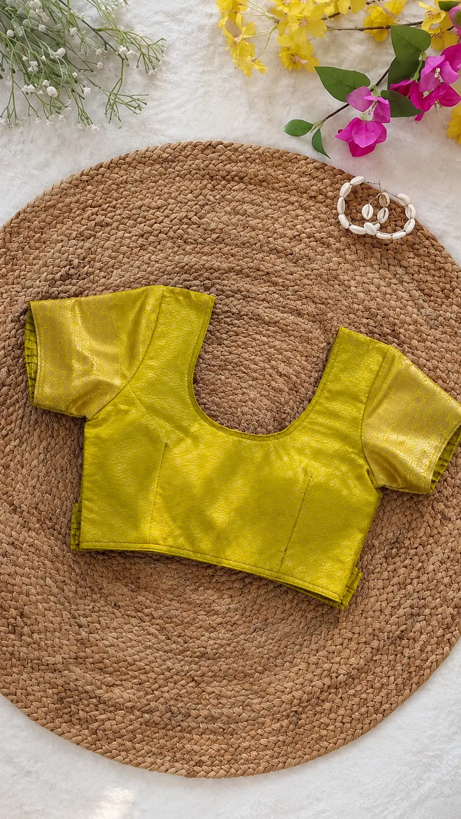 Golden lime silk blouse with short sleeves on a woven mat